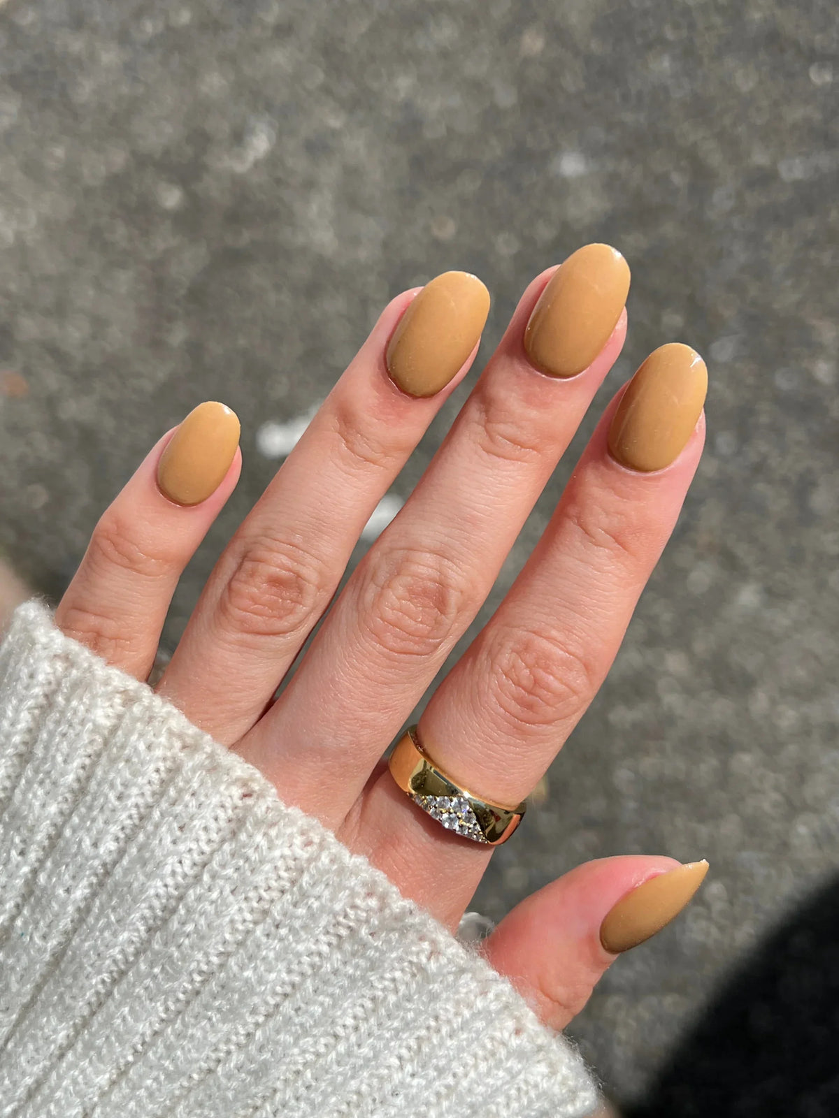 Hand met lange amandelvormige nagels in matte tan en gouden ring met diamantaccenten in herfst bundel product
