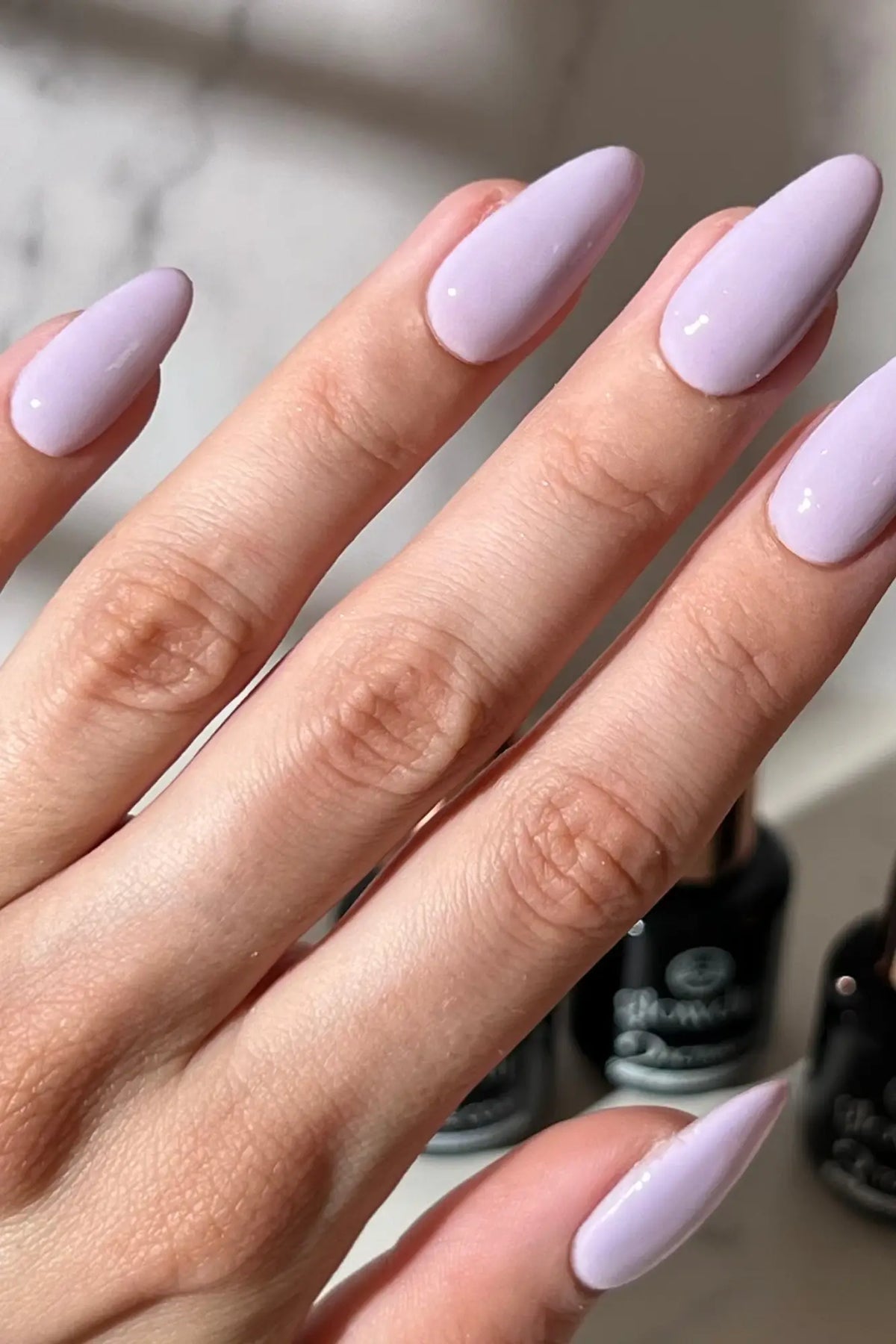 Lavendelgekleurde lange amandelvormige nagels met glanzende afwerking tonen de sterkte van dipping powder