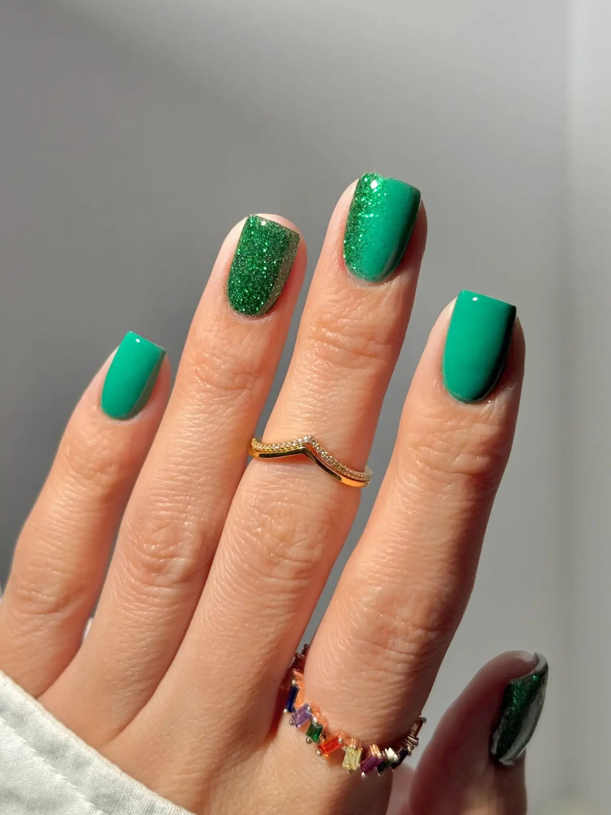 Vibrante smaragdgroene nagellak met glitterfinish op wijsvinger en matte afwerking op andere nagels in gezondste nageloptie artikel